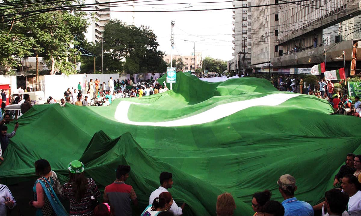 Px13-066 KARACHI: Aug13 – People hold a long national flag during a demonstration organized by Gender Interactive Alliance in connection with Independence Day outside Karachi Press Club. ONLINE PHOTO by Anwar Abbas