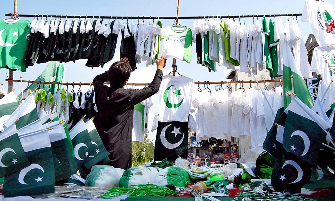 APP03-13 ISLAMABAD: August 13 – A vendor displaying national flags and other stuff to attract the customers at his roadside setup in connection with Independence Day celebrations. APP photo by Saeed-ul-Mulk
